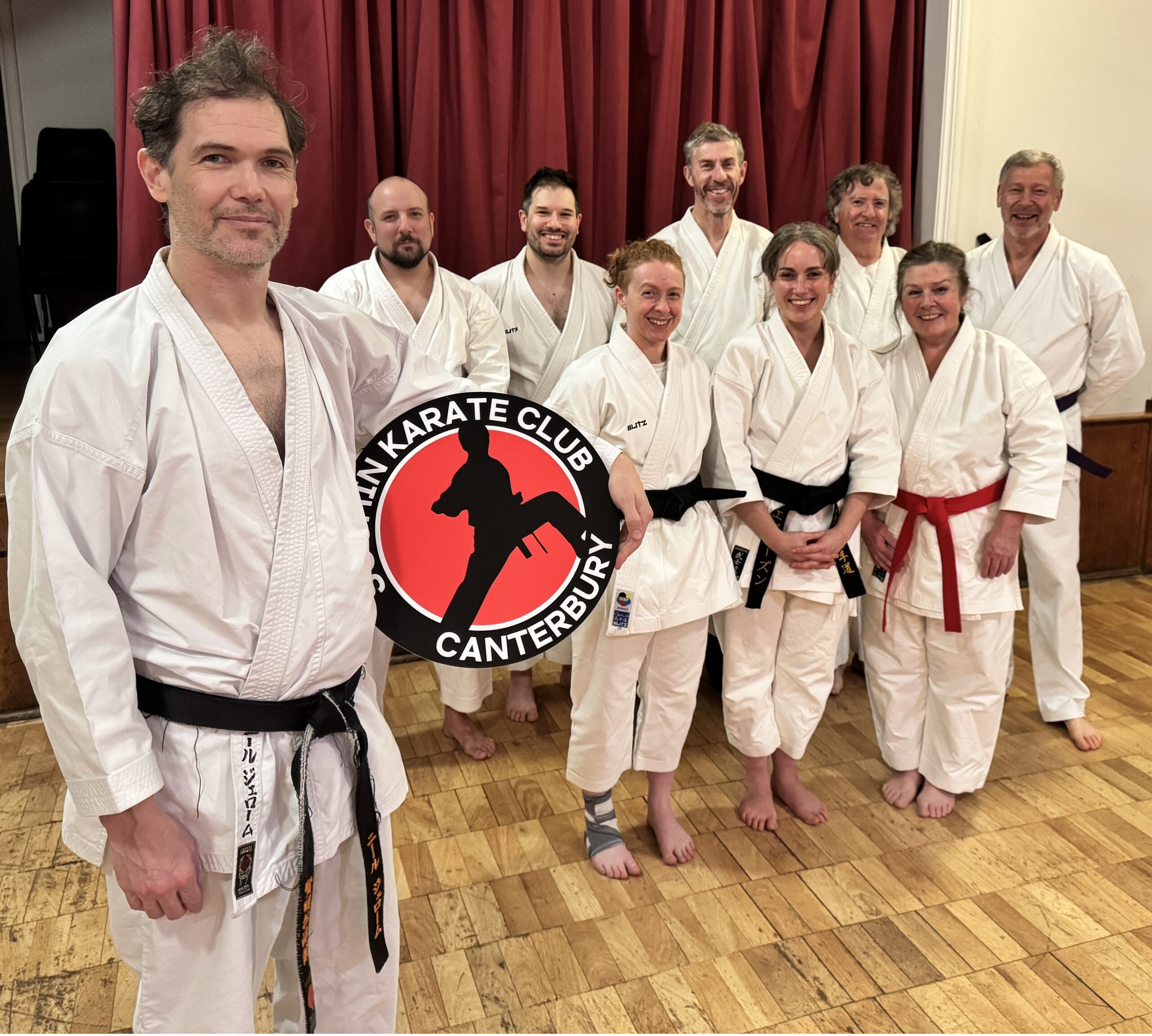 Sensei Neil Jerome holding club logo cheered on by club members